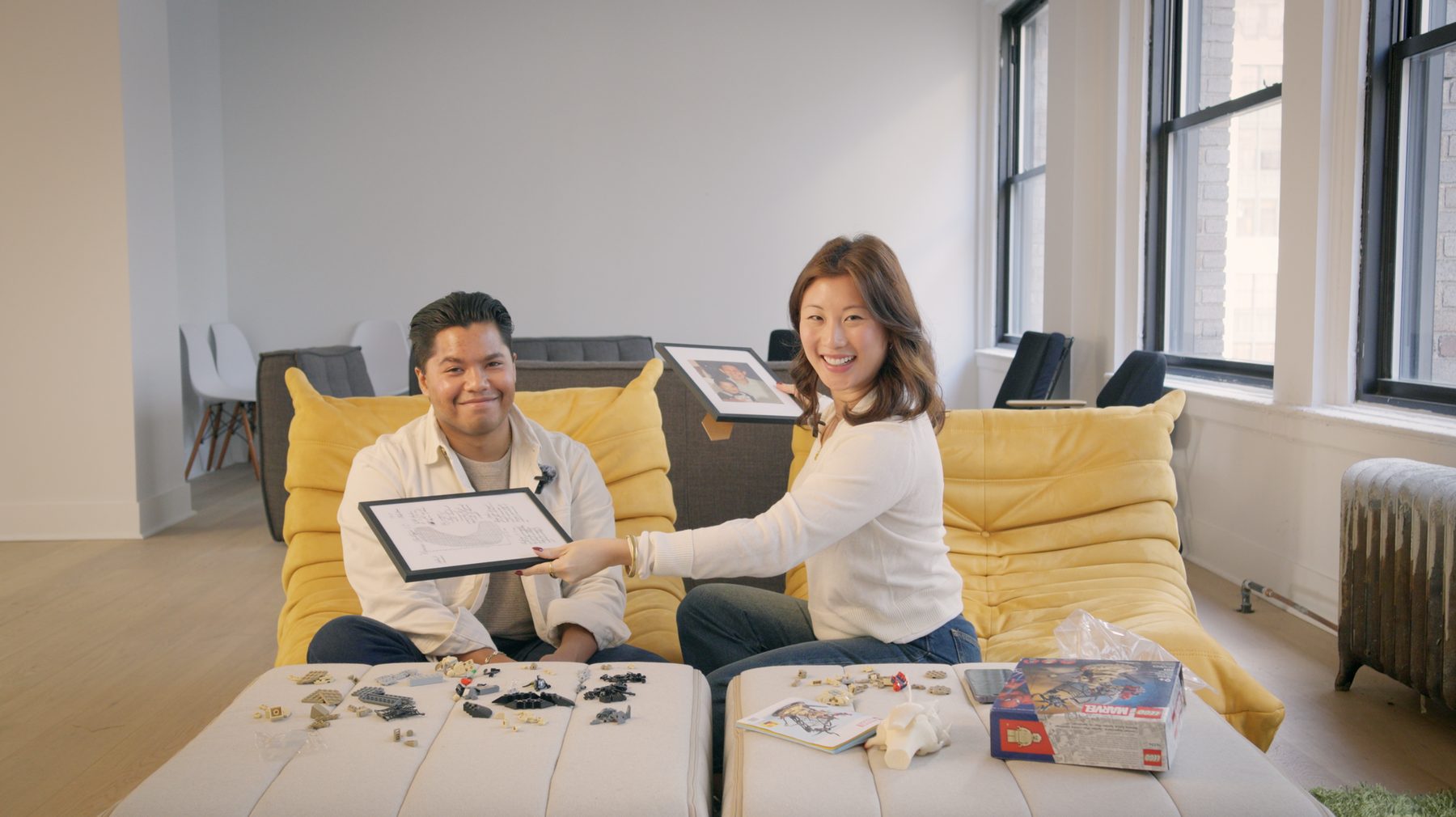 An On-Site host hands framed prints to her guest on a yellow sofa